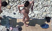Mörkhårig topless snygging visar upp sin kropp på en strand