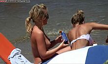Pacar berambut pirang memamerkan payudara mereka dan tubuh seksi di pantai